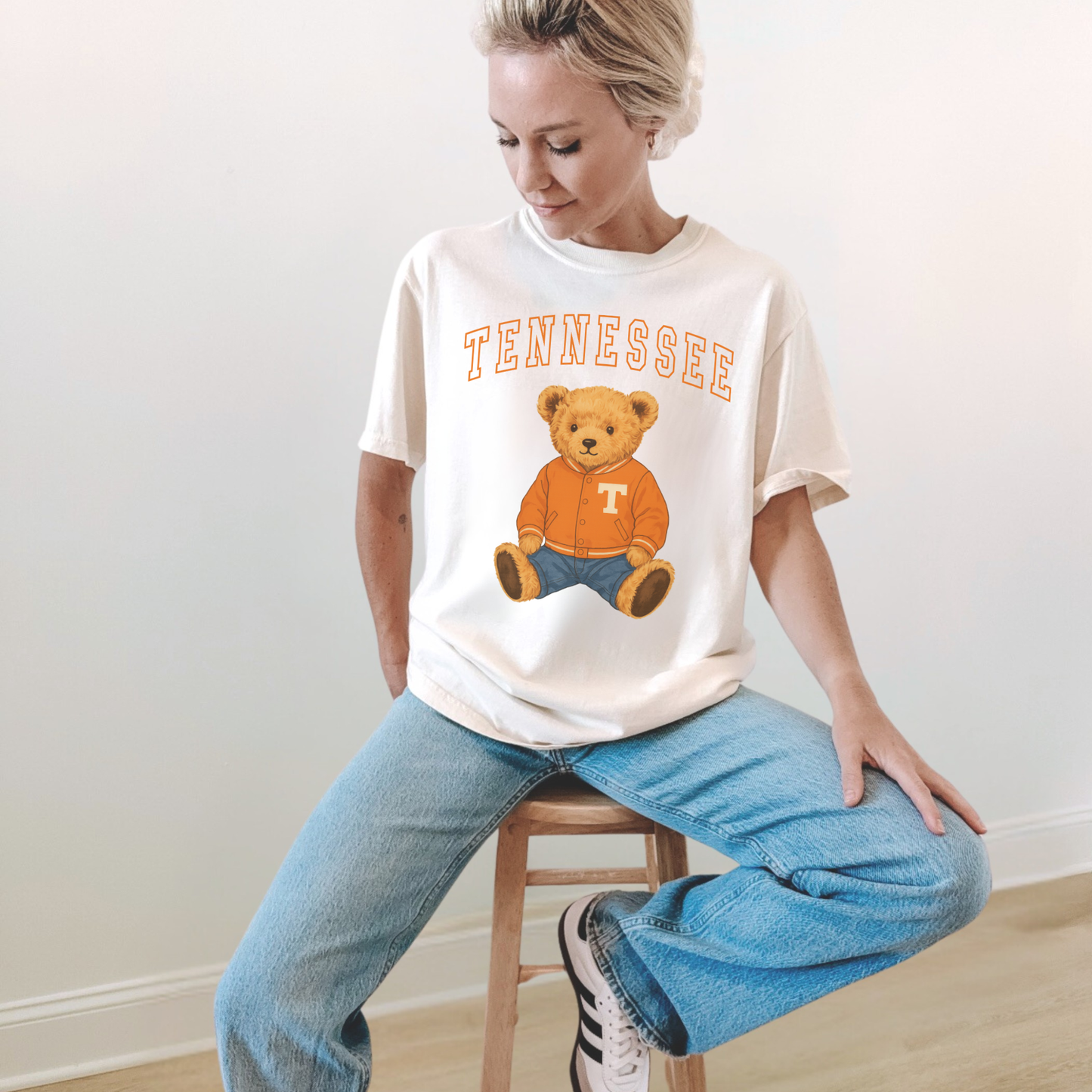 Woman wearing an ivory Tennessee teddy bear graphic tee with vintage orange collegiate lettering and cute game day teddy bear design.