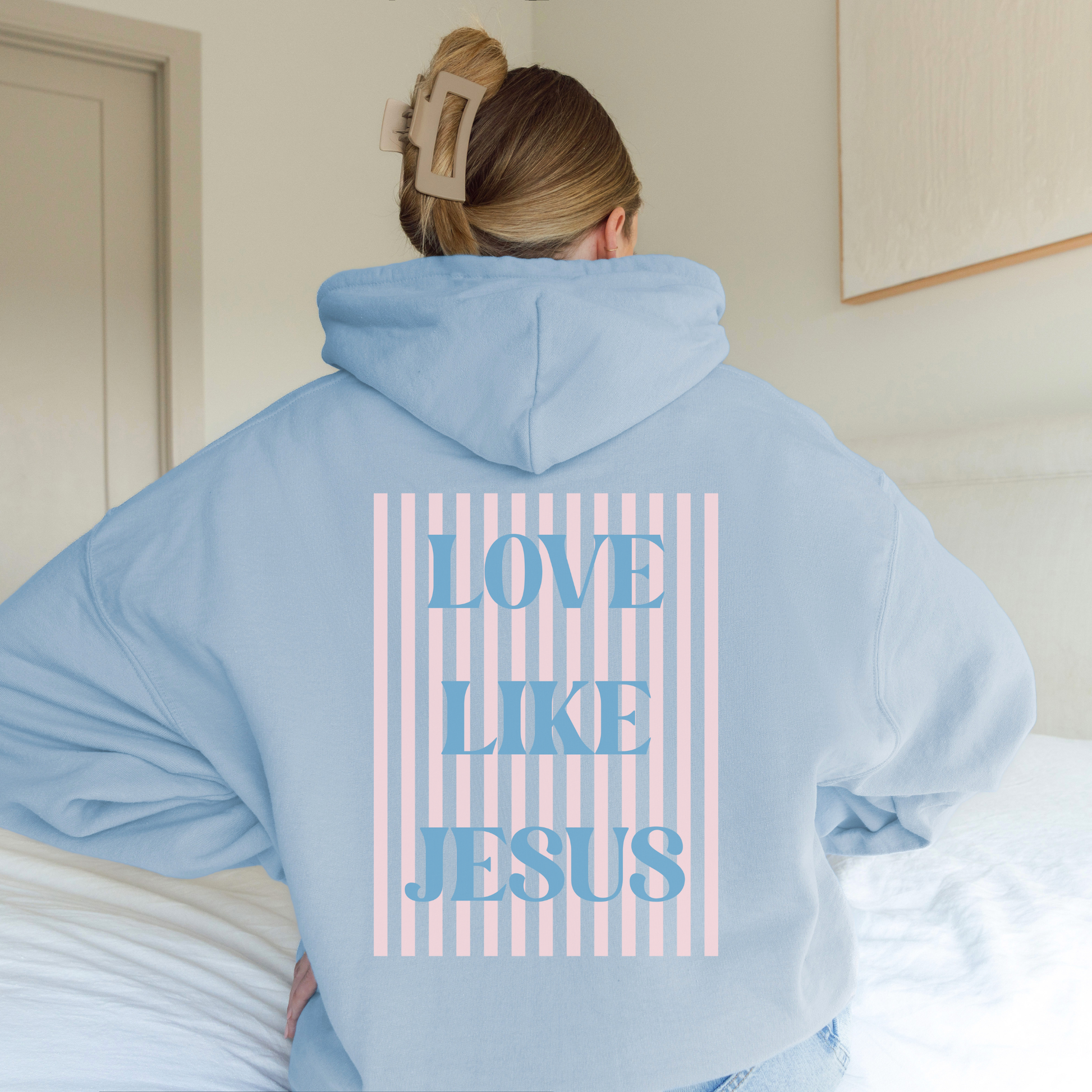 Light blue hoodie with large striped “Love Like Jesus” back print, Christian striped graphic design.