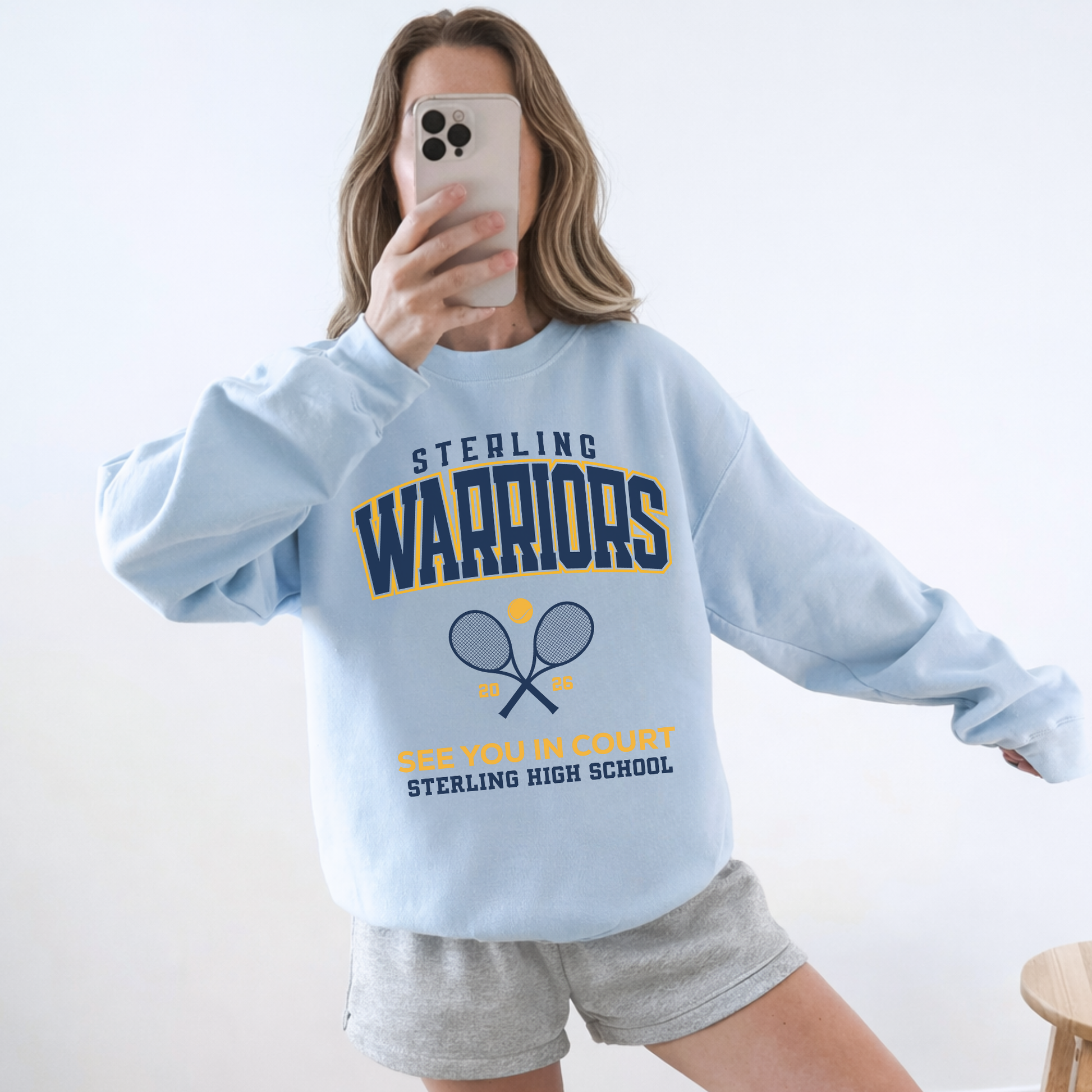 Woman wearing a light blue Sterling Warriors Tennis sweatshirt styled casually