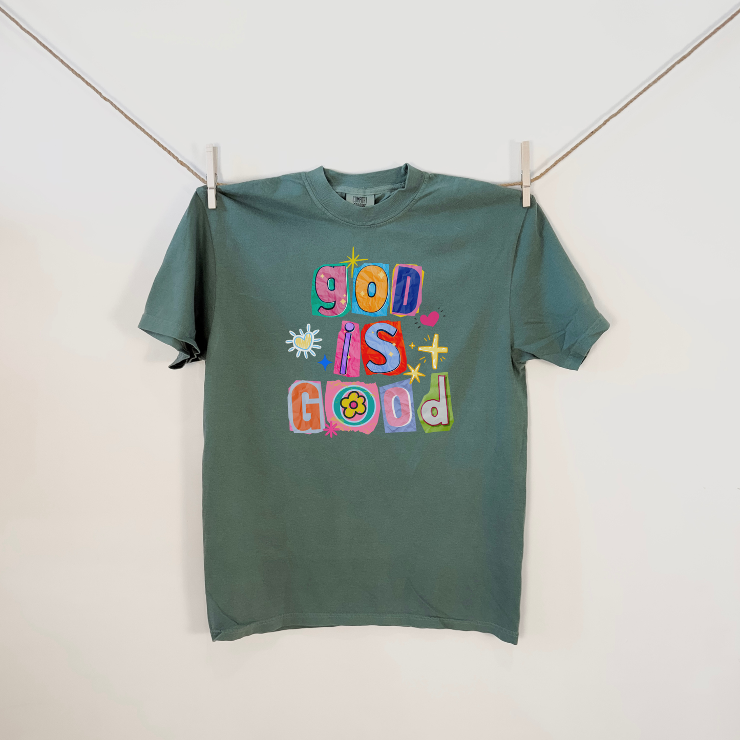 Green Comfort Colors God Is Good faith graphic t-shirt hanging flat