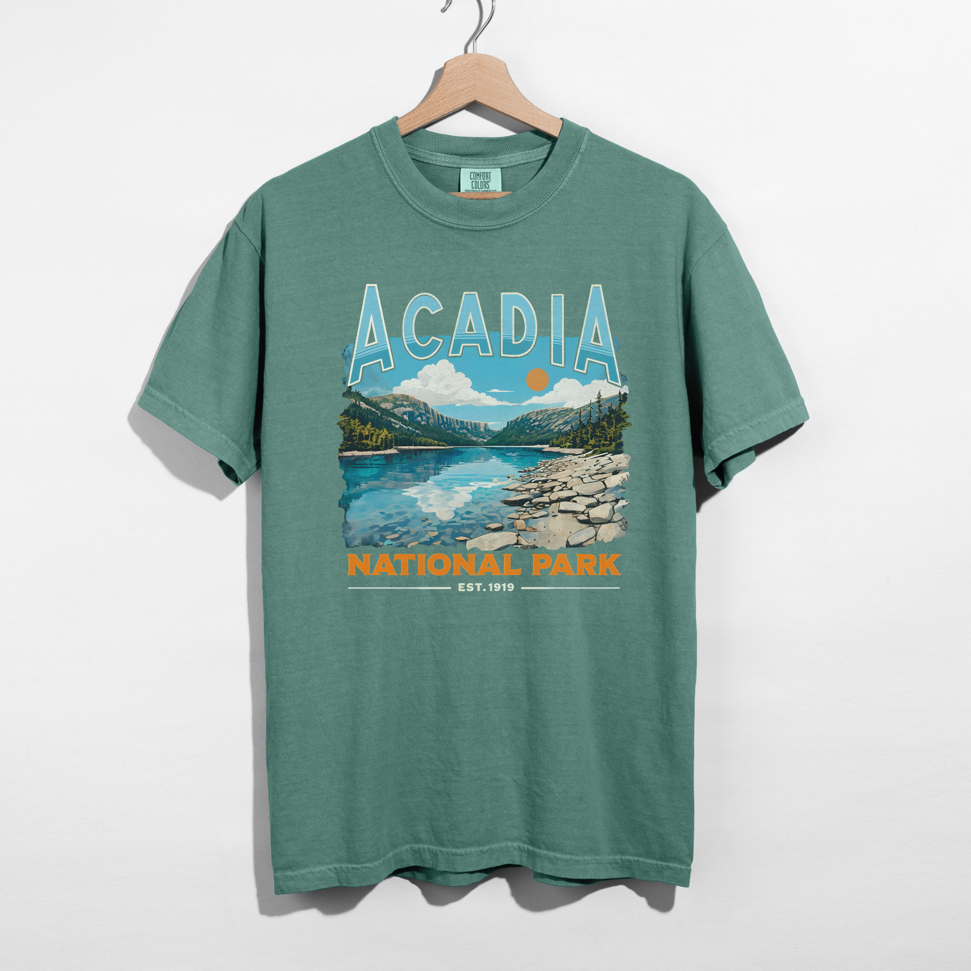 green Acadia National Park vintage graphic t-shirt hanging on wooden hanger with colorful scenic national park print.