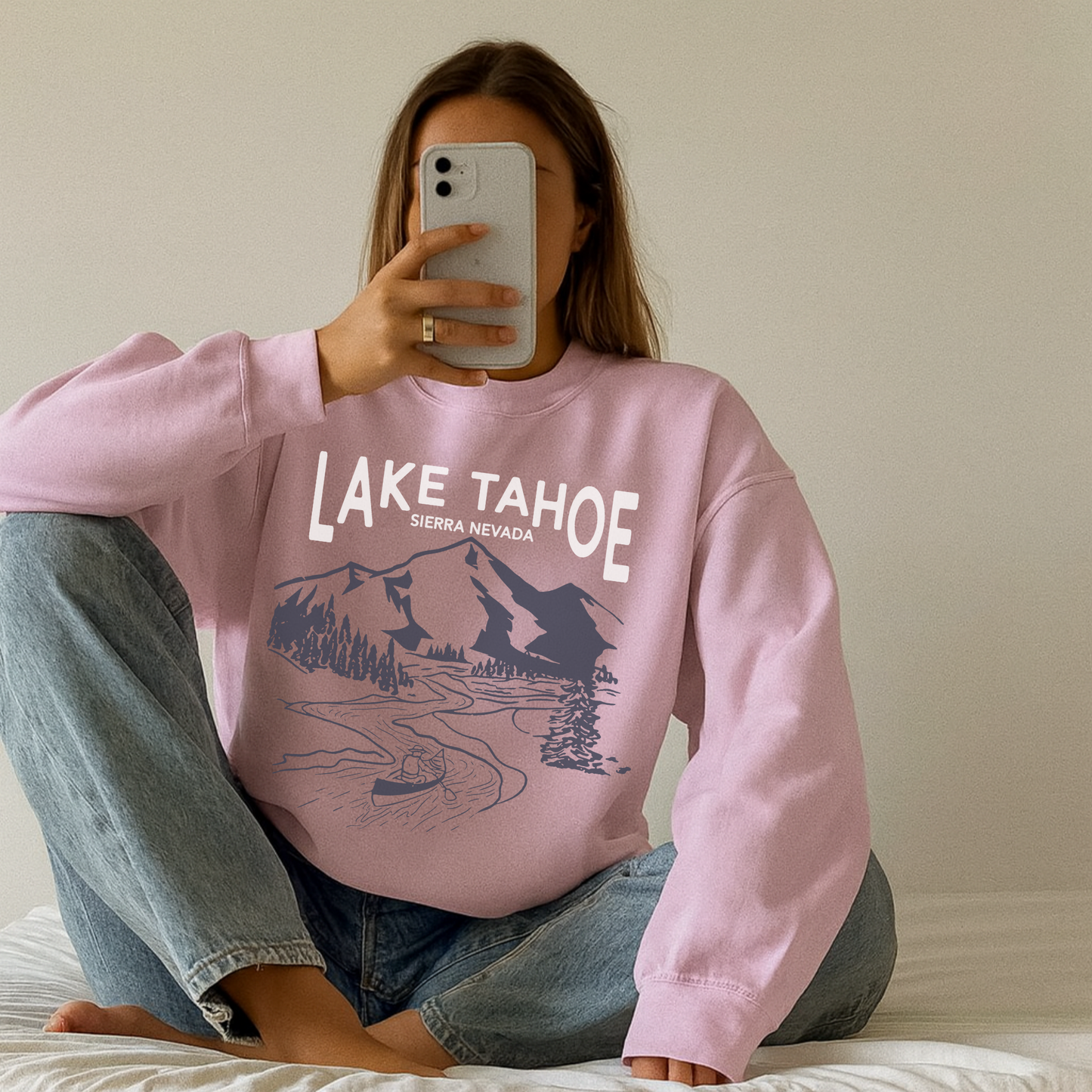 Woman sitting cross-legged wearing pink Lake Tahoe Sierra Nevada mountain graphic sweatshirt