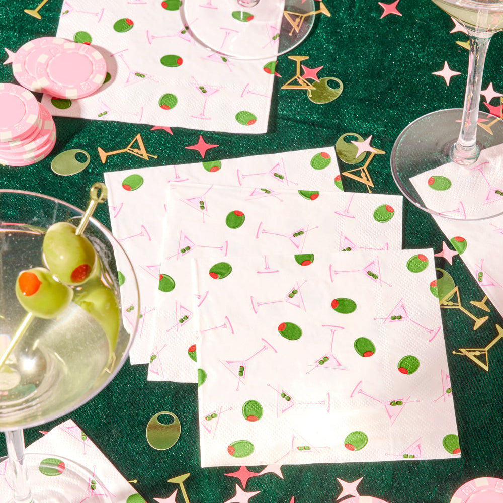 Pink martini cocktail napkins with green olive print styled on glitter green party table with martini glasses and pink poker chips