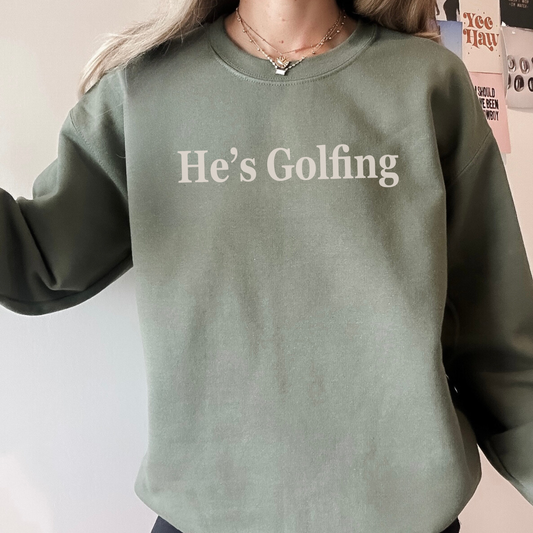 Green sweatshirt with 'He's Golfing' text worn by a person