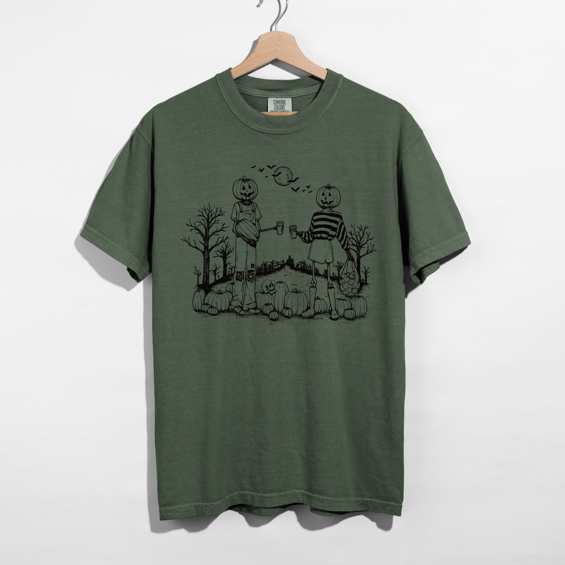 Moss green Halloween graphic tee featuring spooky pumpkin friends with bats, pumpkins, trees, and moon in a vintage autumn illustration.