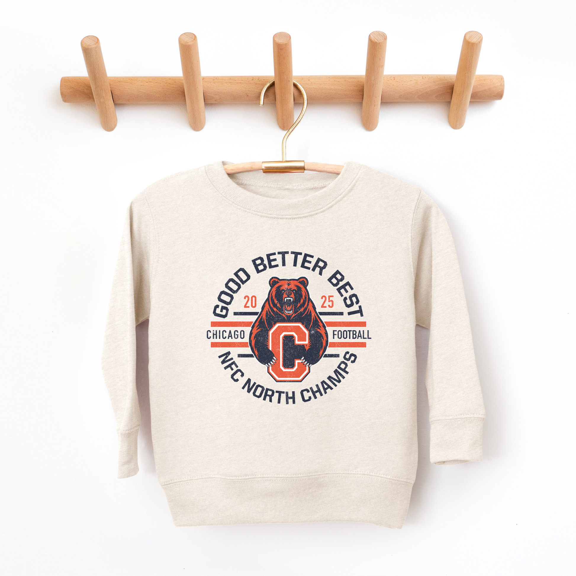 Beige sweatshirt with a graphic design of a bear and text on a wooden hanger against a white background