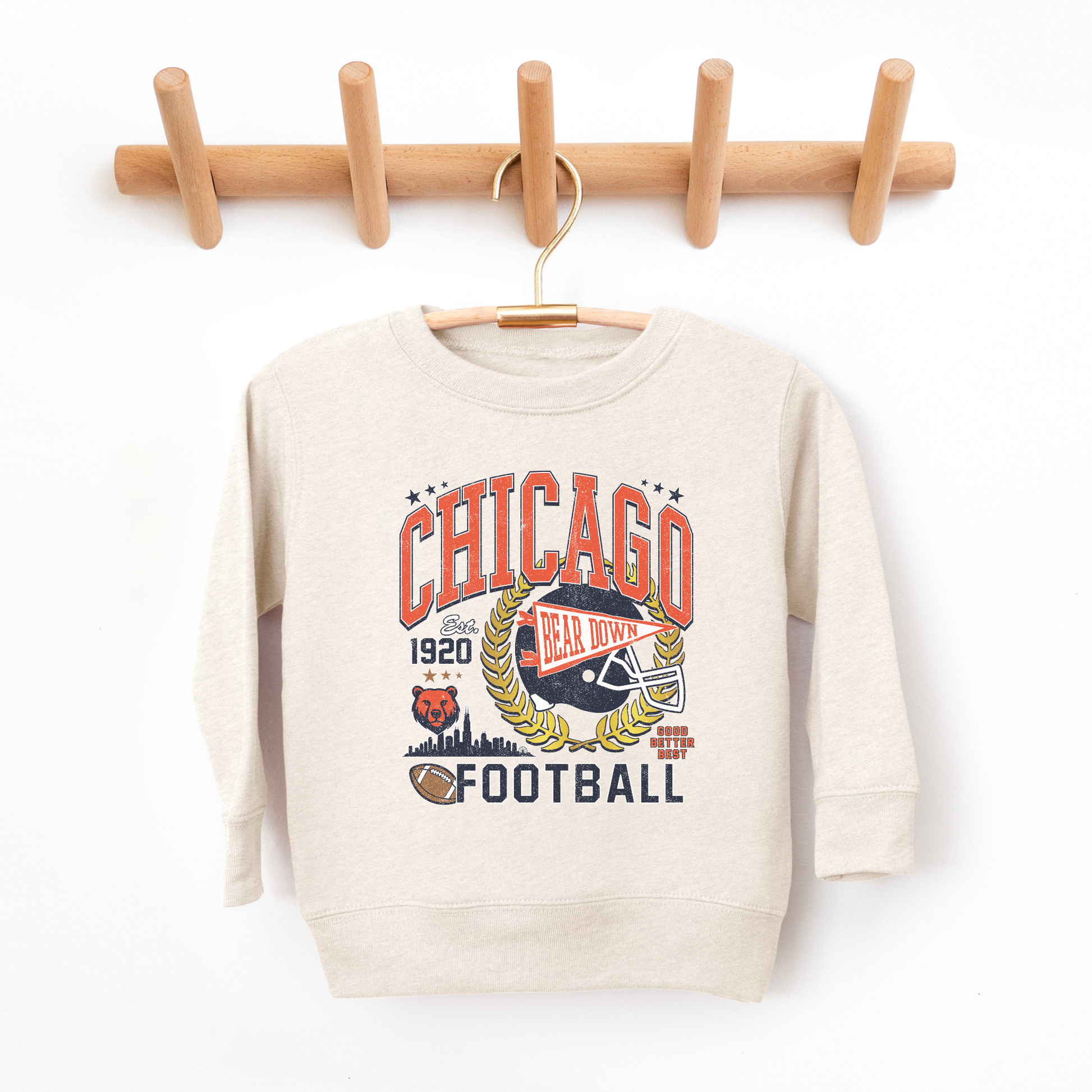 Beige sweatshirt with Chicago-themed design hanging on a wooden rack against a white background
