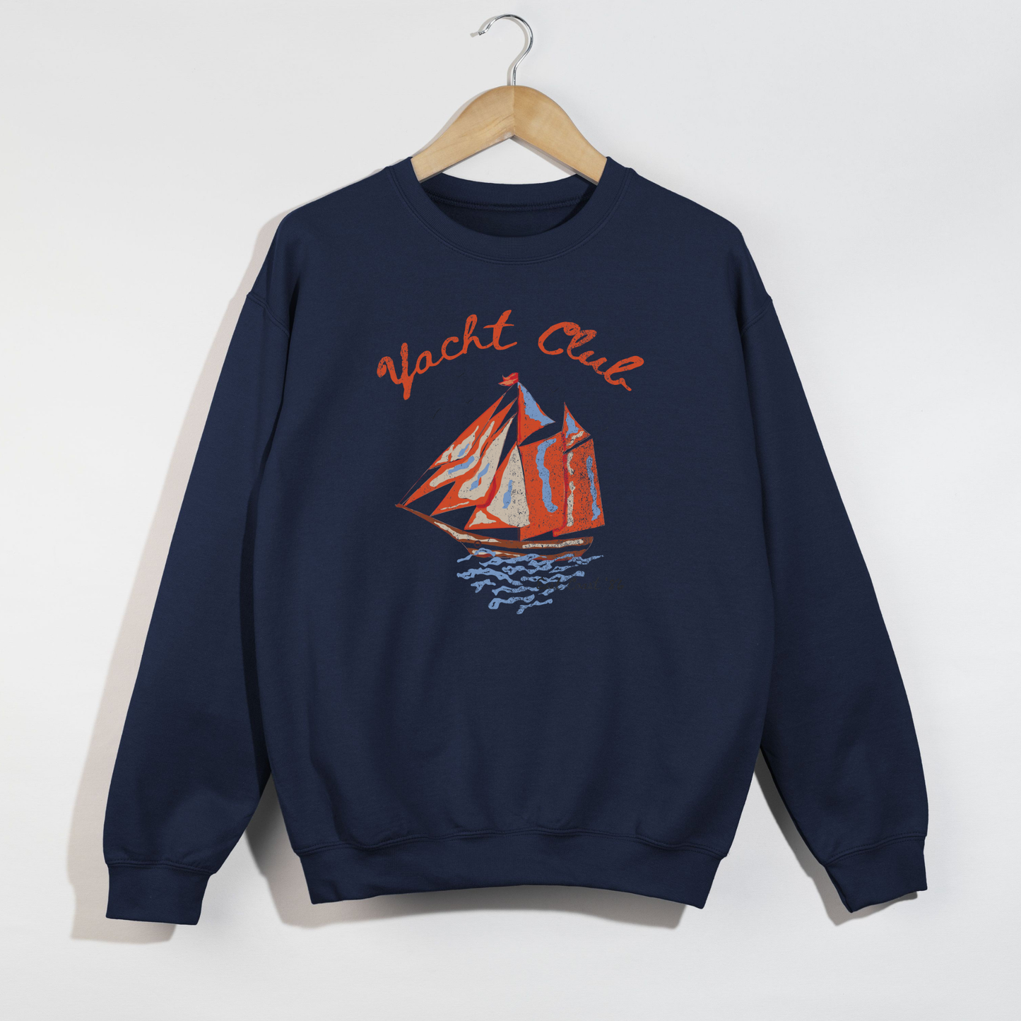 navy yacht club graphic sweatshirt with sailboat design laid flat on hanger