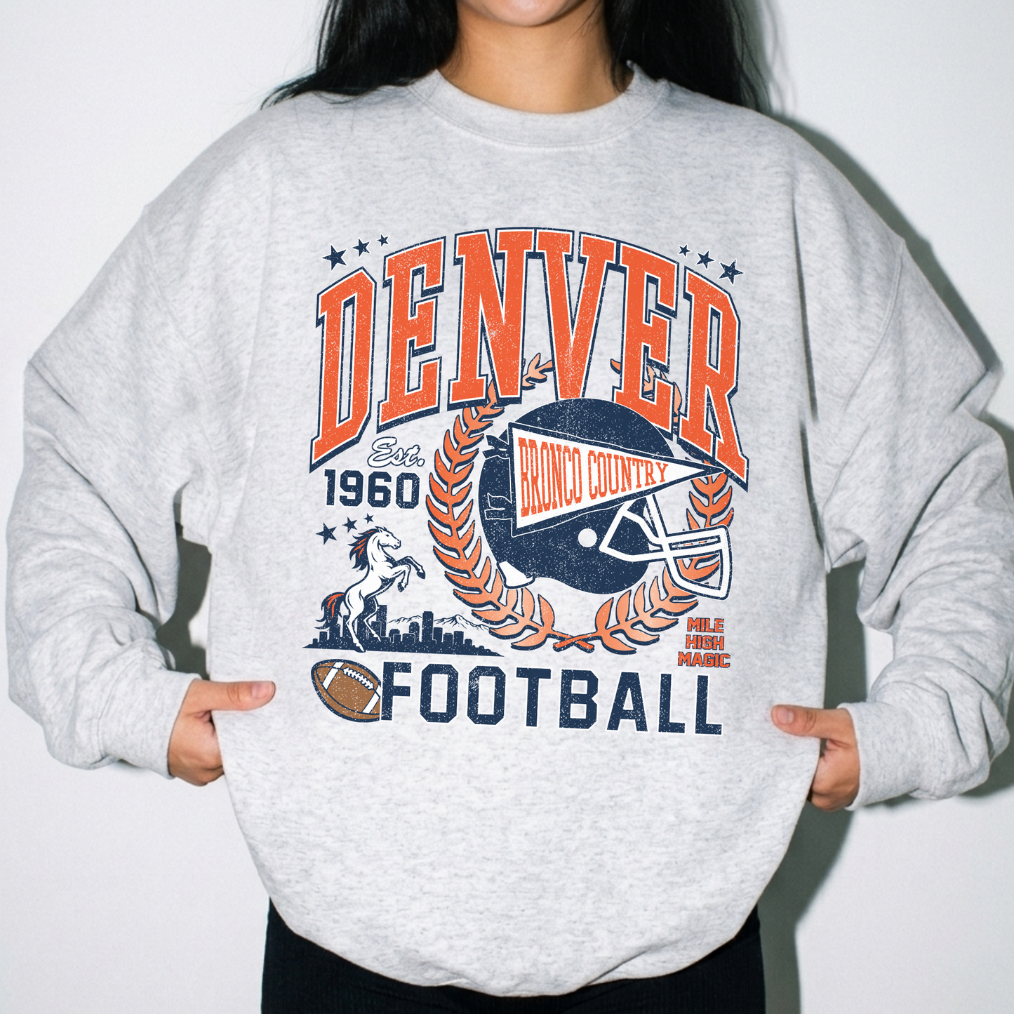 Woman wearing oatmeal heather Denver football sweatshirt with retro orange and navy game day graphic