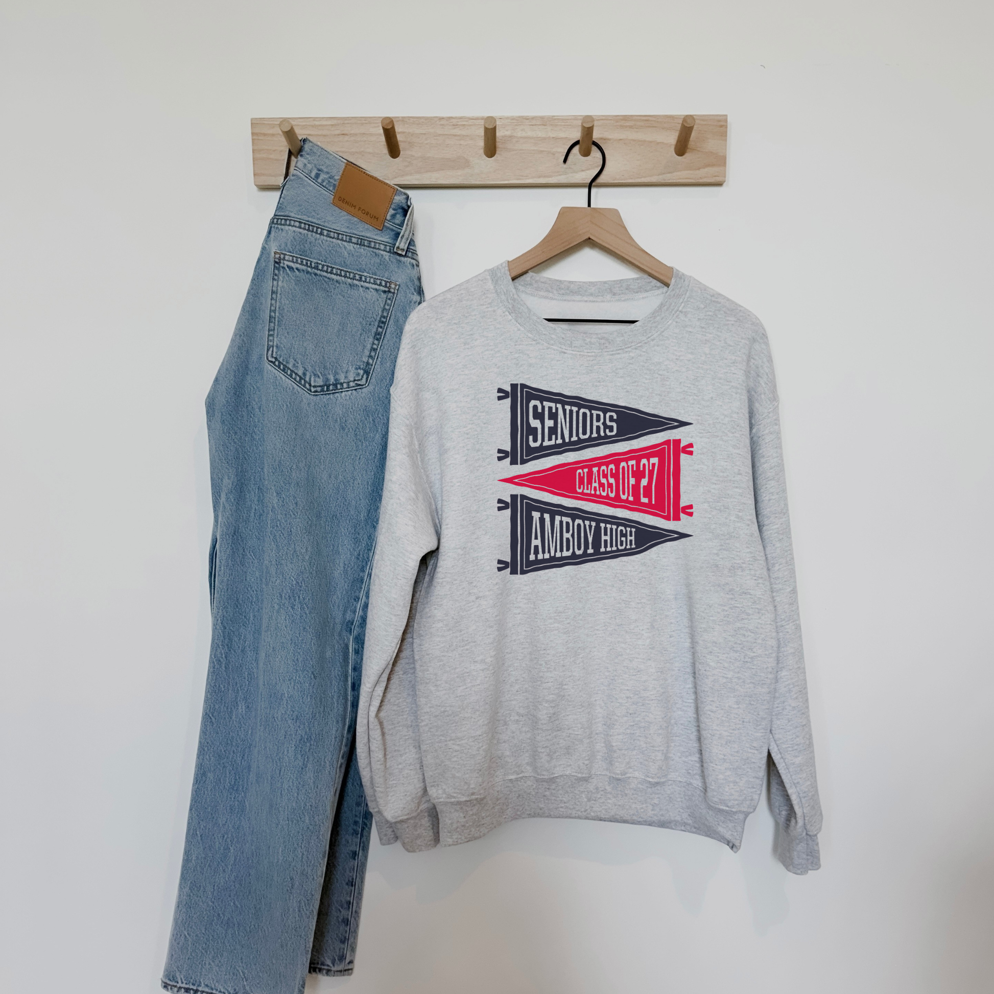 Heather grey Amboy High Seniors Class of 2027 sweatshirt featuring vintage navy and red varsity pennant graphics displayed with light wash denim jeans.