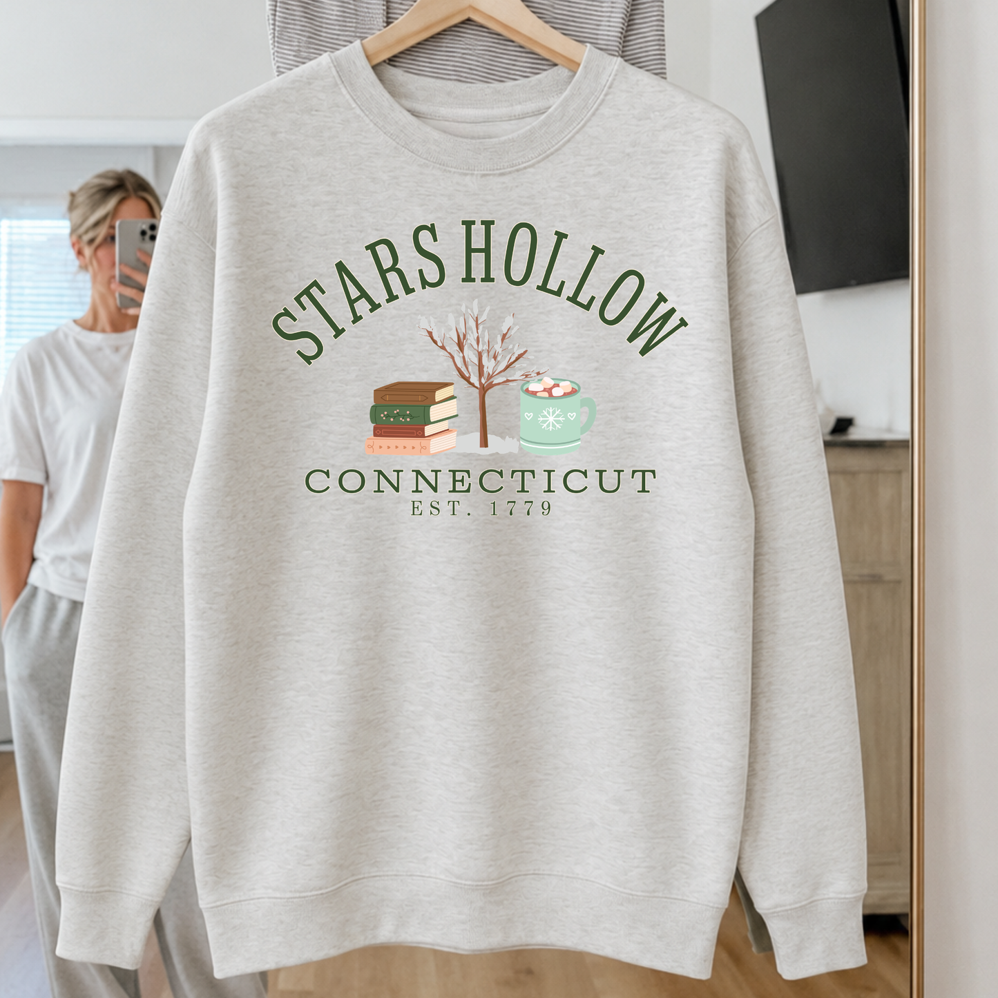 Stars Hollow Connecticut premium winter sweatshirt with stacked books snow covered tree and mint hot cocoa mug