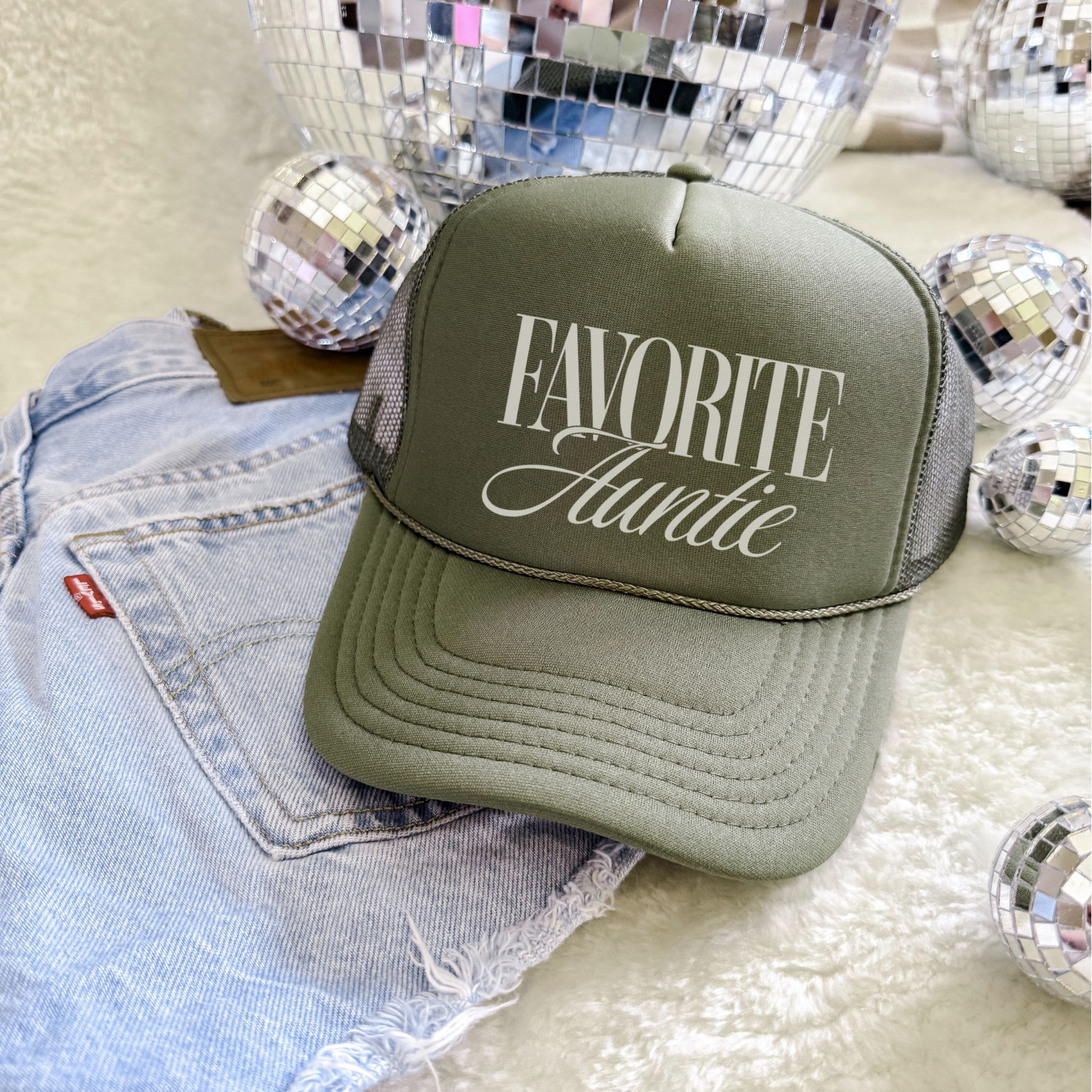 Green cap with 'Favorite Auntie' text on denim fabric with disco balls in the background