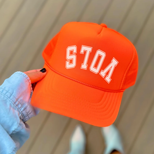 Orange cap with 'vols' text held by a person against a neutral background