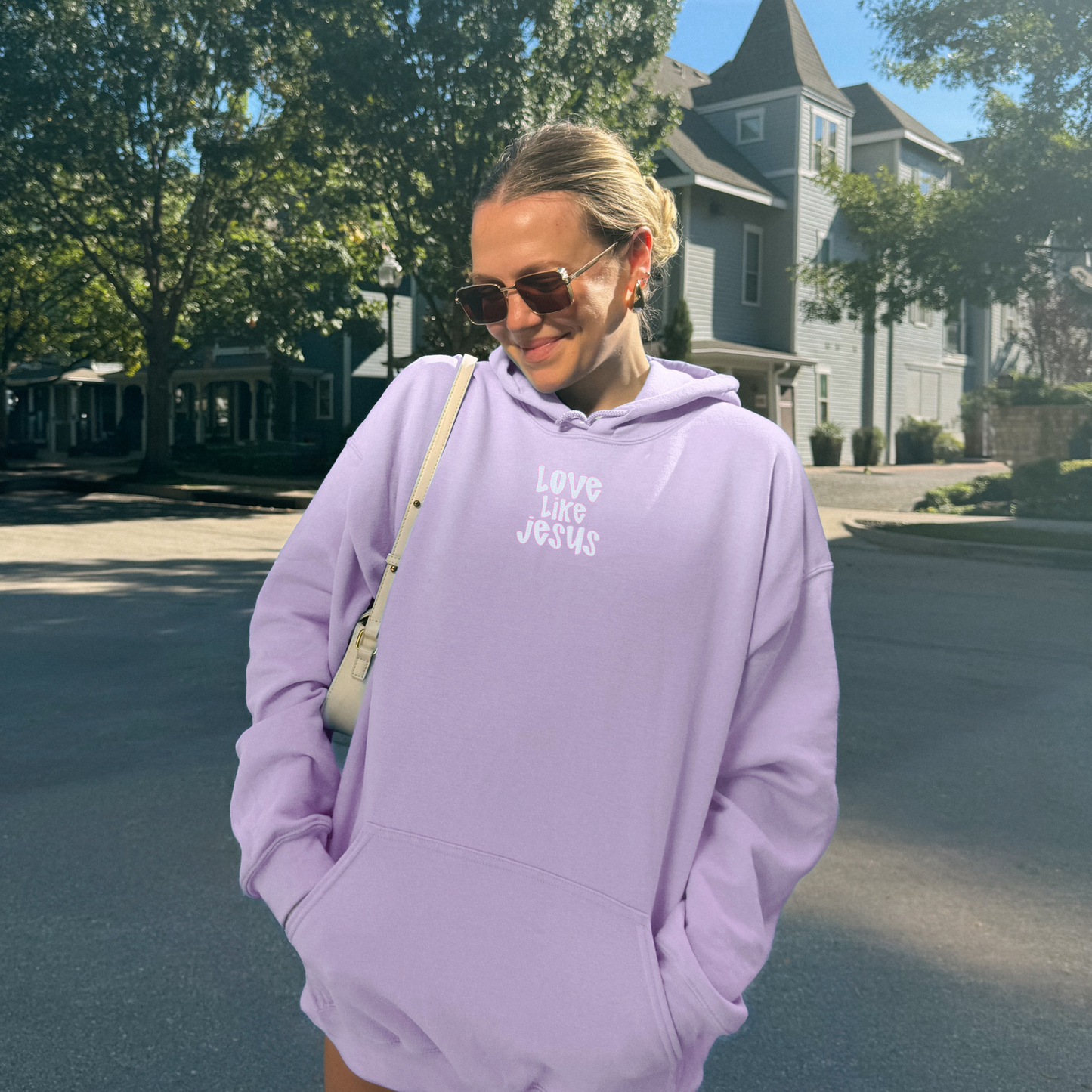 Woman wearing orchid hoodie with small front “Love Like Jesus” print, oversized Christian sweatshirt.