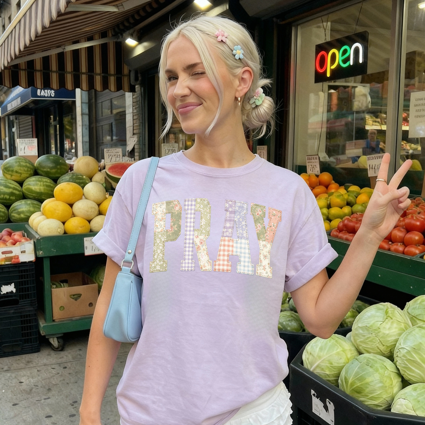 Woman wearing purple PRAY faux patchwork graphic tee styled casually outdoors