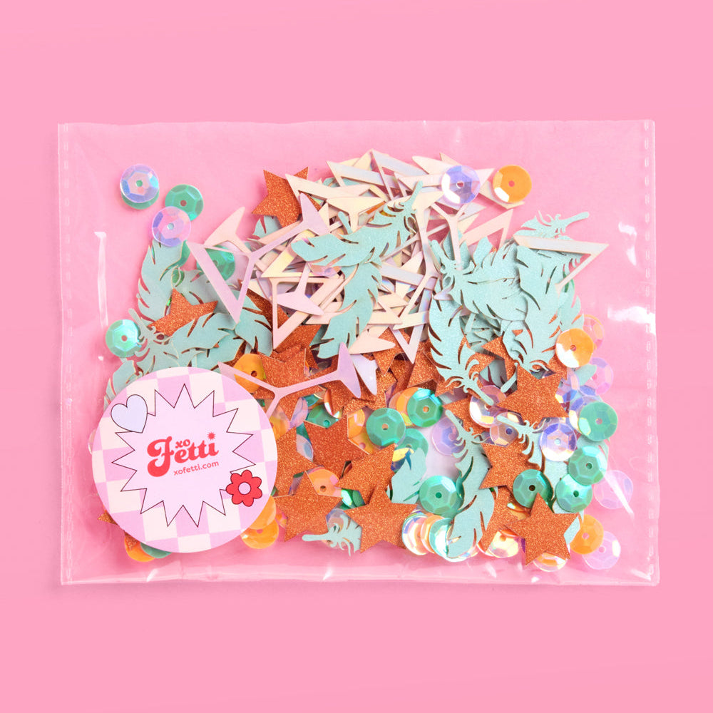 Packaged decorative confetti with colorful shapes on a pink background