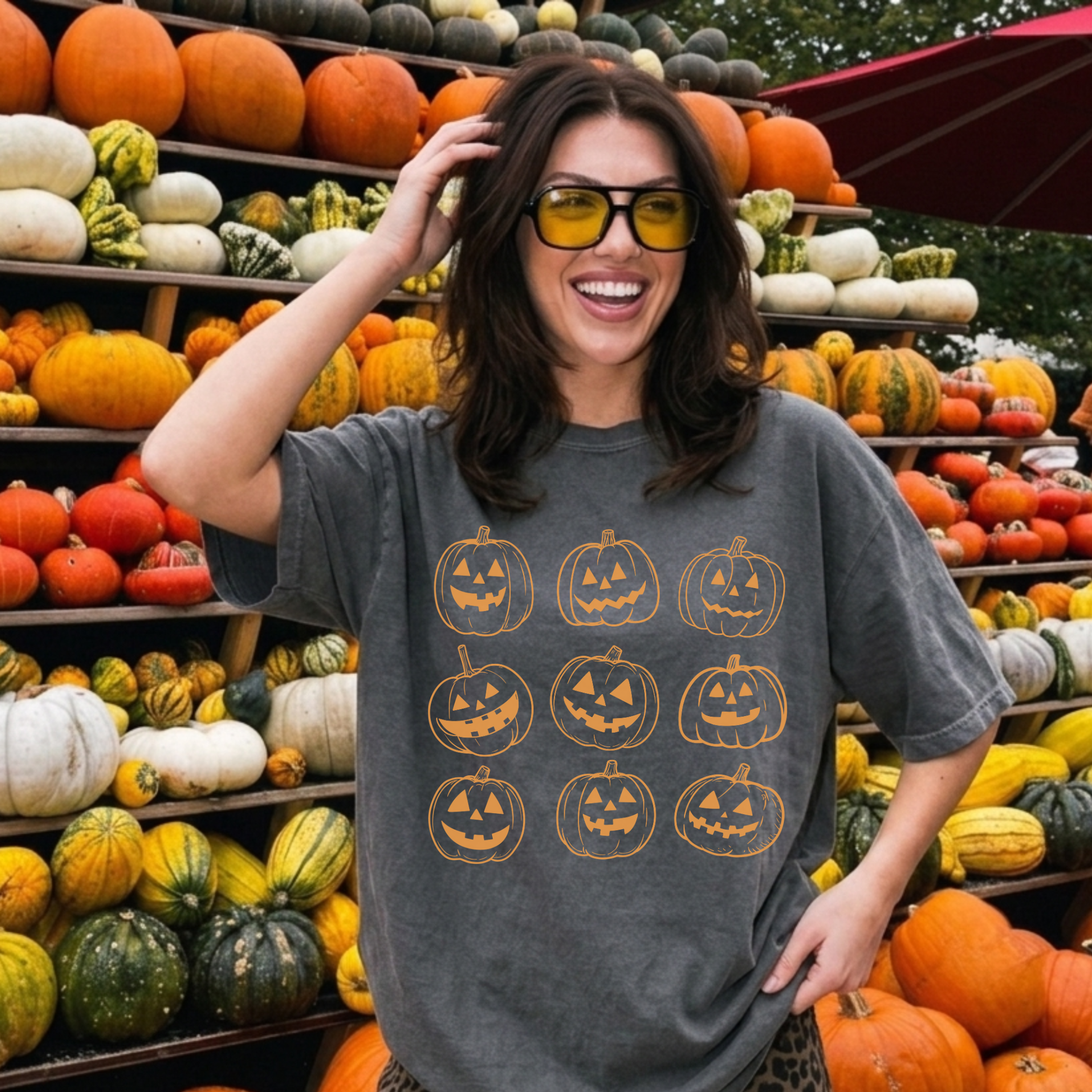 Woman wearing a Comfort Colors Pepper gray Halloween t-shirt featuring nine vintage orange jack o' lantern pumpkins at a pumpkin patch.