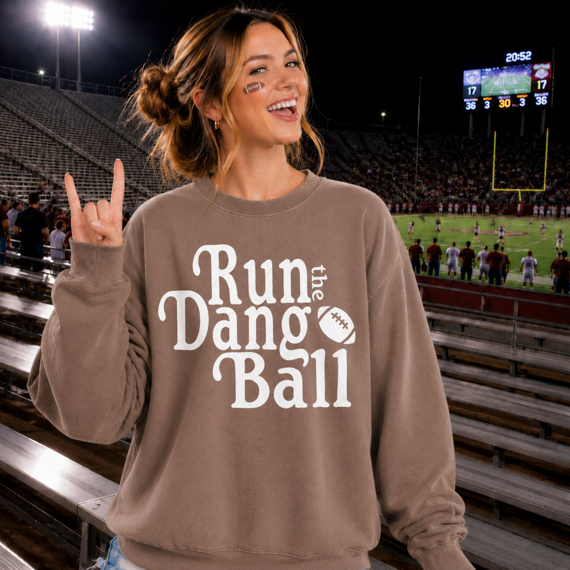 Woman wearing Run the Dang Ball football sweatshirt at a football stadium on game day