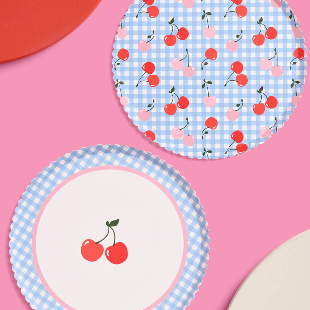 Two paper plates with cherry design on a pink background