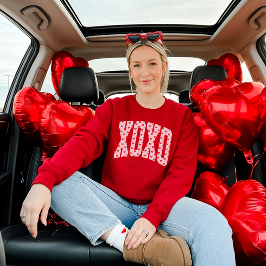 Model wearing red XO heart print crewneck sweatshirt styled casually with jeans