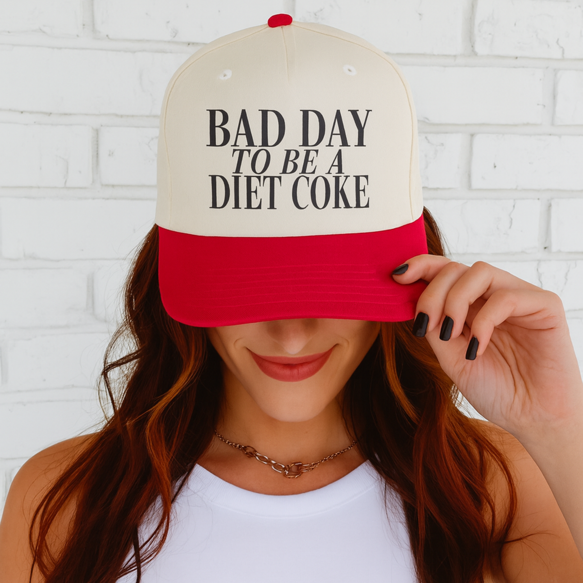 Person wearing a cap with 'Bad Day to be a Diet Coke' text against a white brick wall.