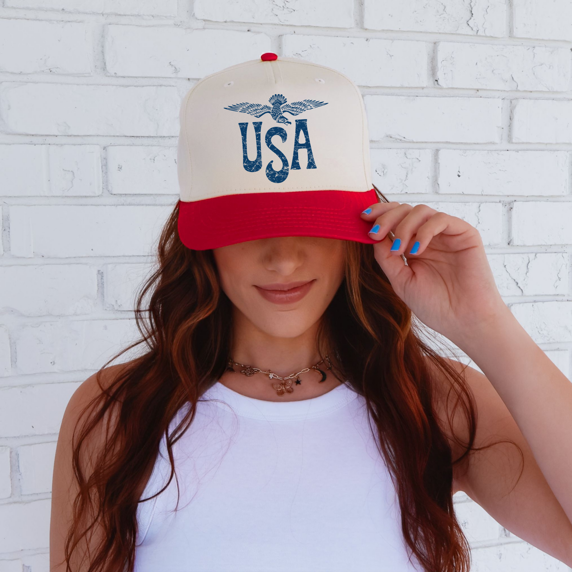 A person wearing a white trucker hat with a red visor featuring an eagle graphic and the text 'USA' on the front.