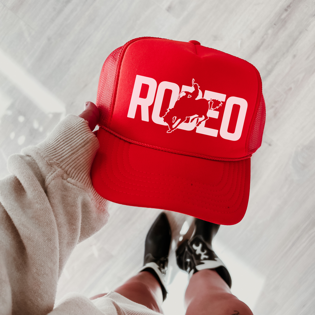 Red and white rodeo trucker hat with bold western graphic styled on denim with sunglasses