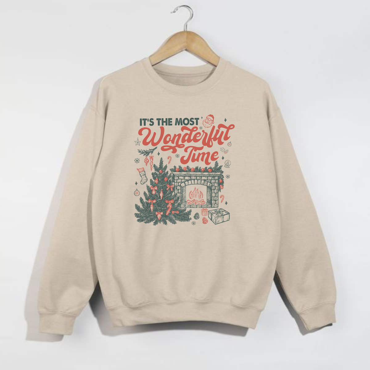 Sand-colored Christmas sweatshirt hanging on a wooden hanger, printed with “It’s the Most Wonderful Time” festive design in red and green.