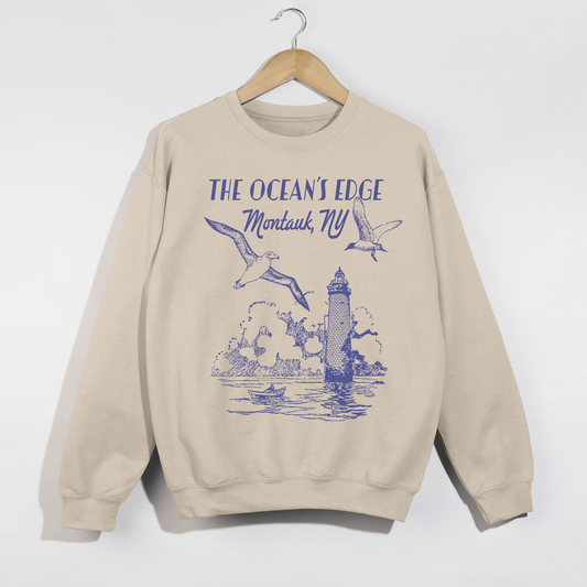 "Sand-colored Montauk coastal lighthouse graphic sweatshirt hanging on wooden hanger."