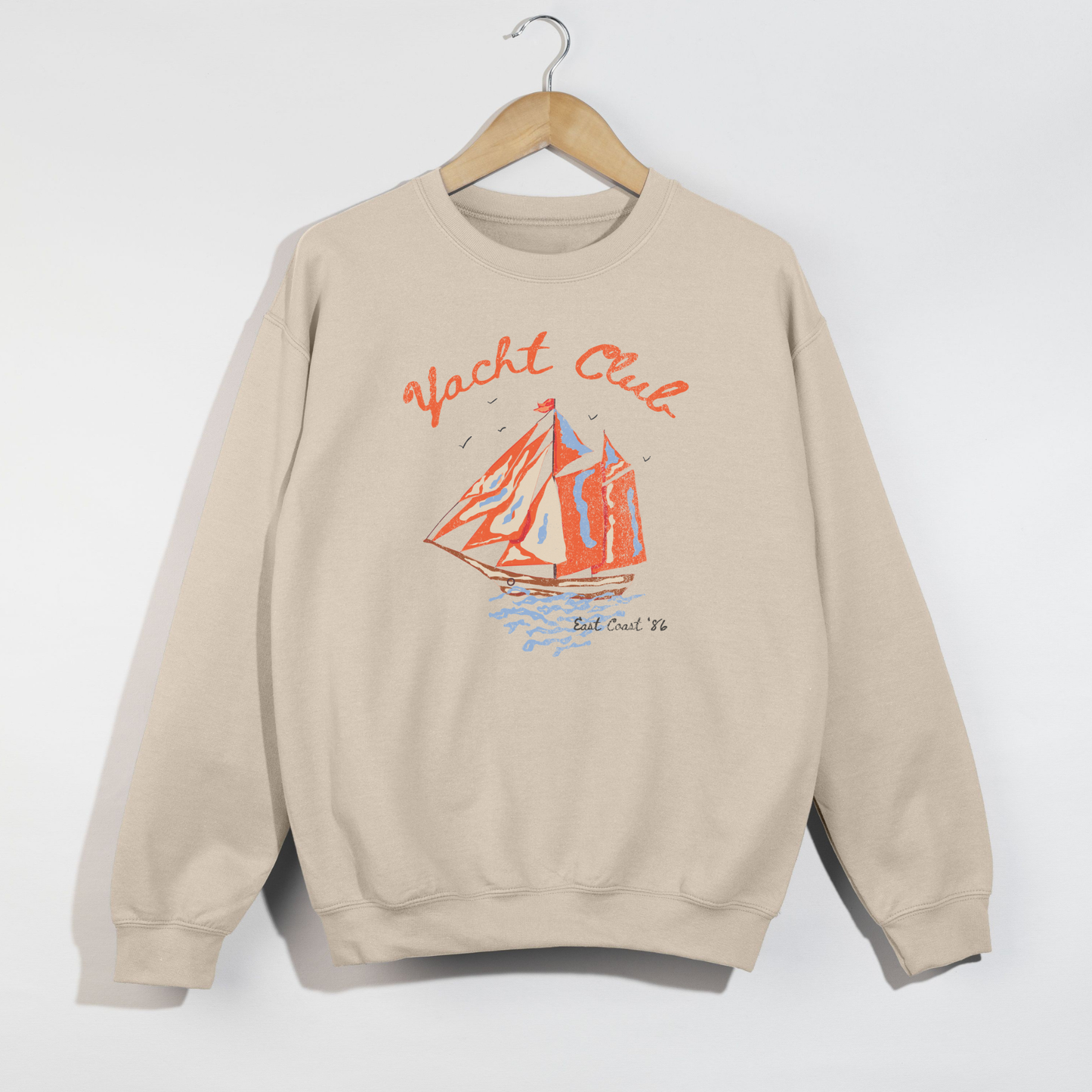 sand beige yacht club crewneck sweatshirt with colorful sailboat graphic on hanger