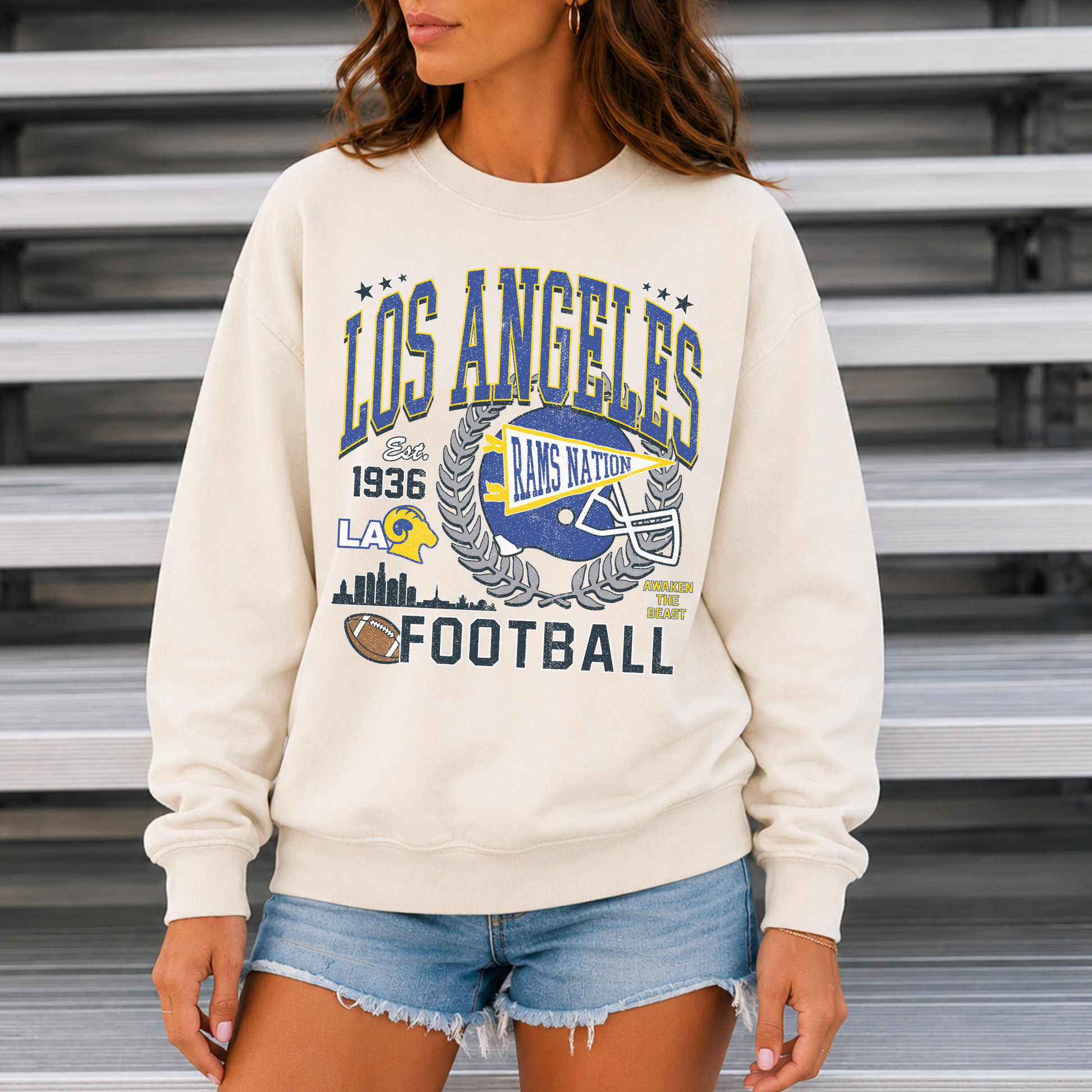 Woman wearing cream Los Angeles football sweatshirt with blue and gold Rams Nation game day graphic