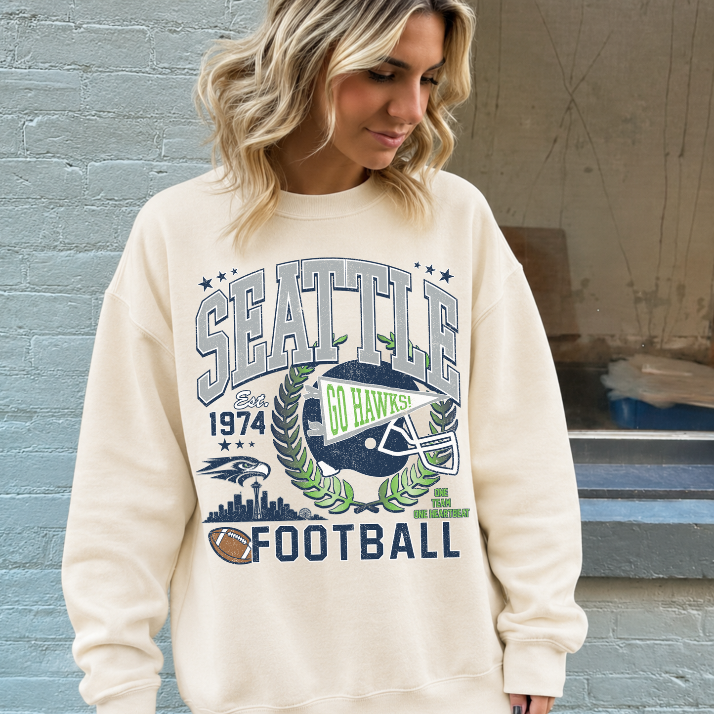 Woman wearing cream Seattle football graphic sweatshirt with vintage navy gray and green football design
