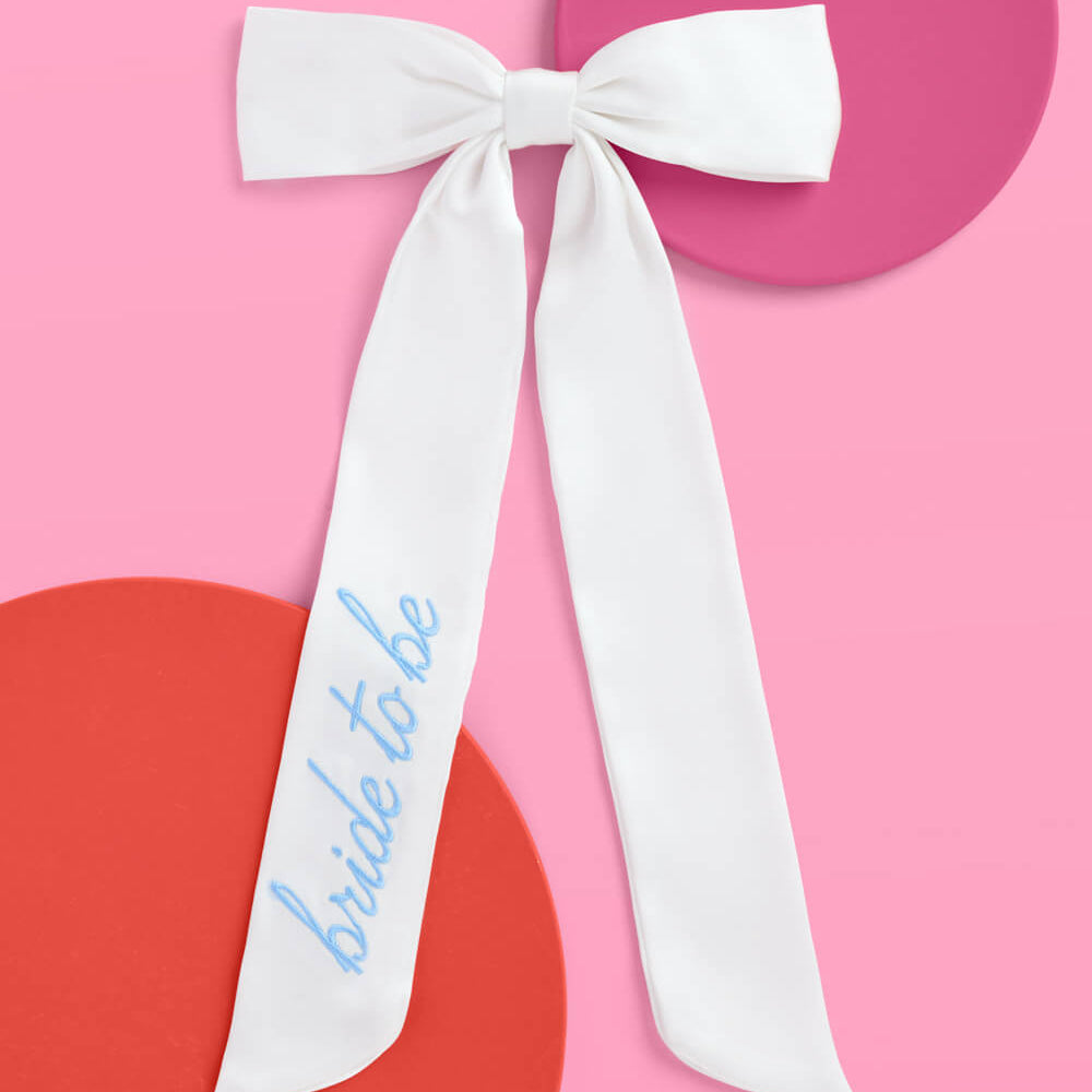 White ribbon with 'bride to be' text on a pink background