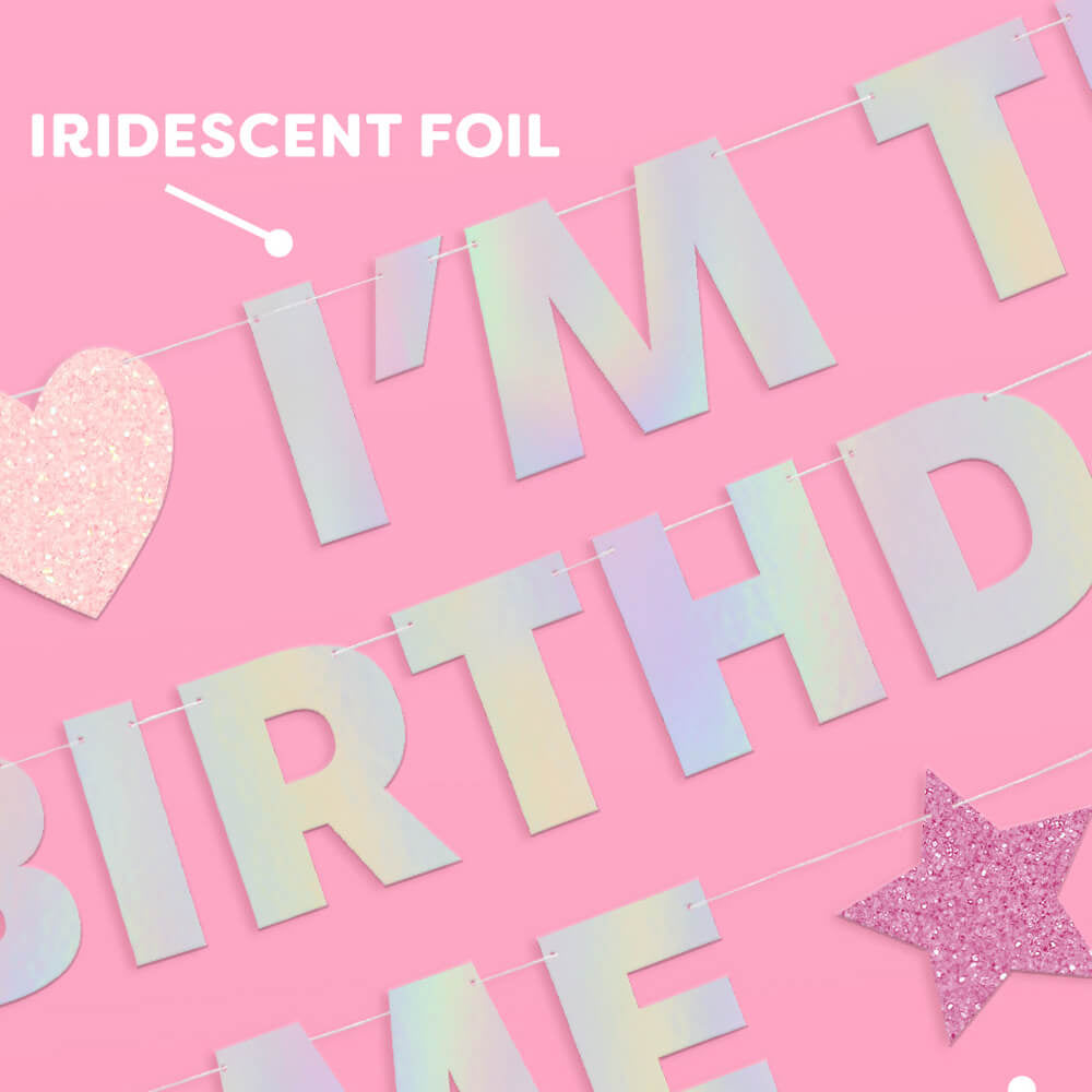 Iridescent foil birthday banner with pink and purple glitter on a pink background