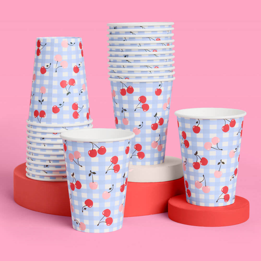 Stacks of paper cups with cherry pattern on a pink background