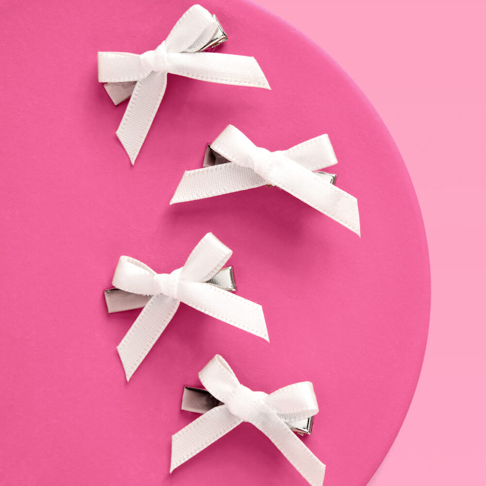 White bows on pink circular object with a pink background