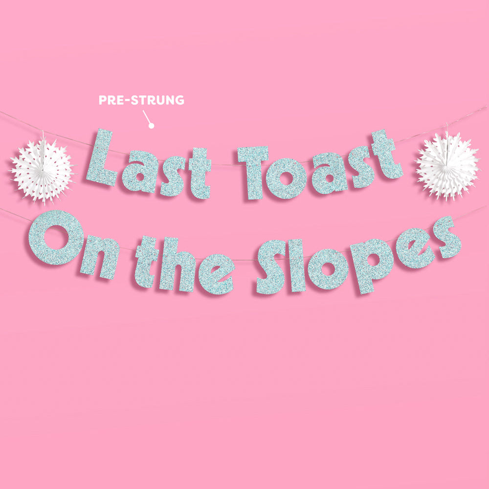 Decorative string with 'Last Toast On the Slopes' text on a pink background