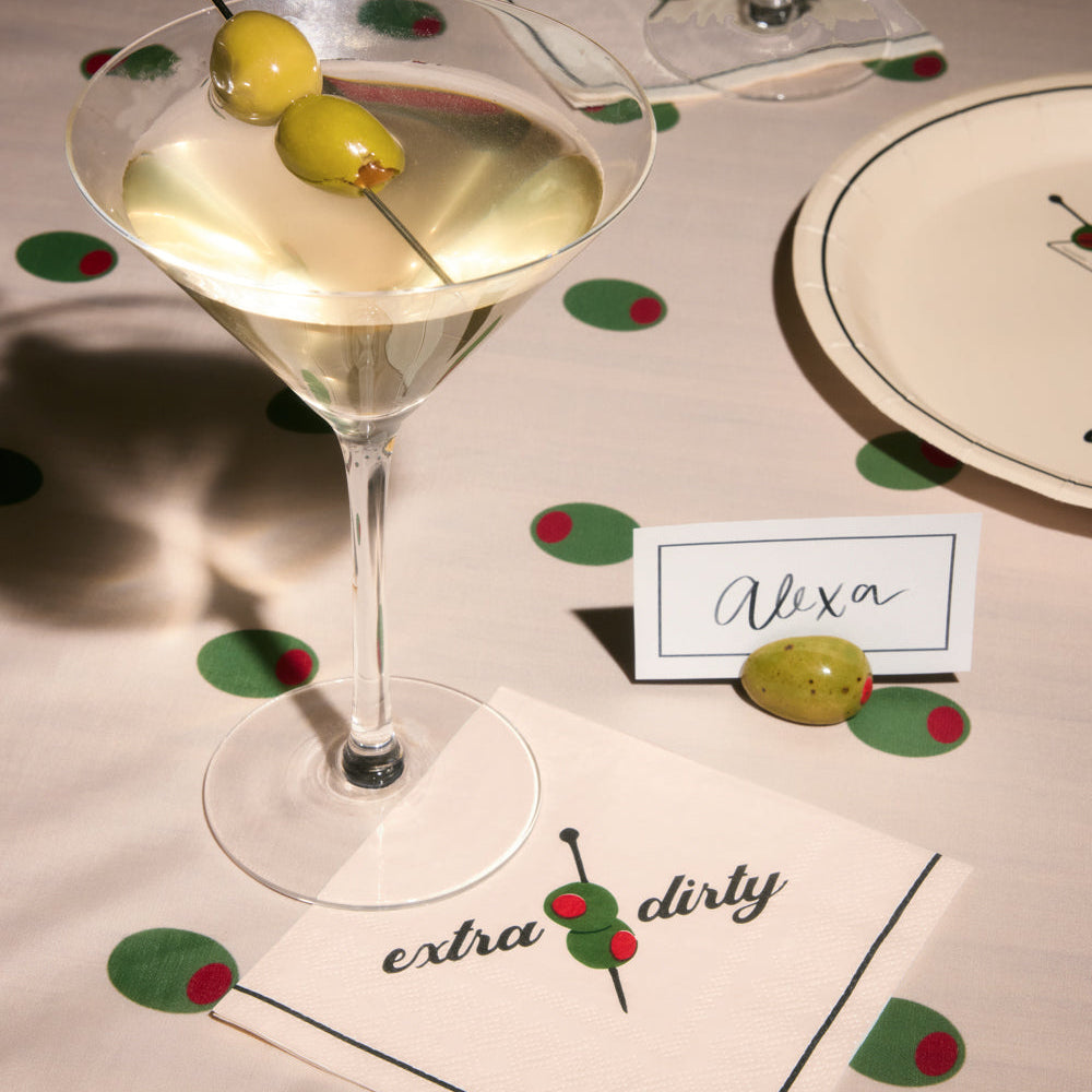 Martini glass with olives on a table setting with 'extra dirty' napkin and place card.