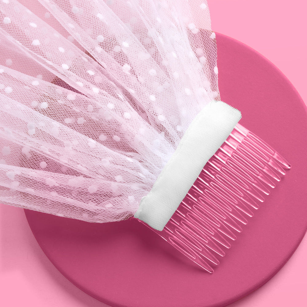 White tulle fabric with a comb on a pink background