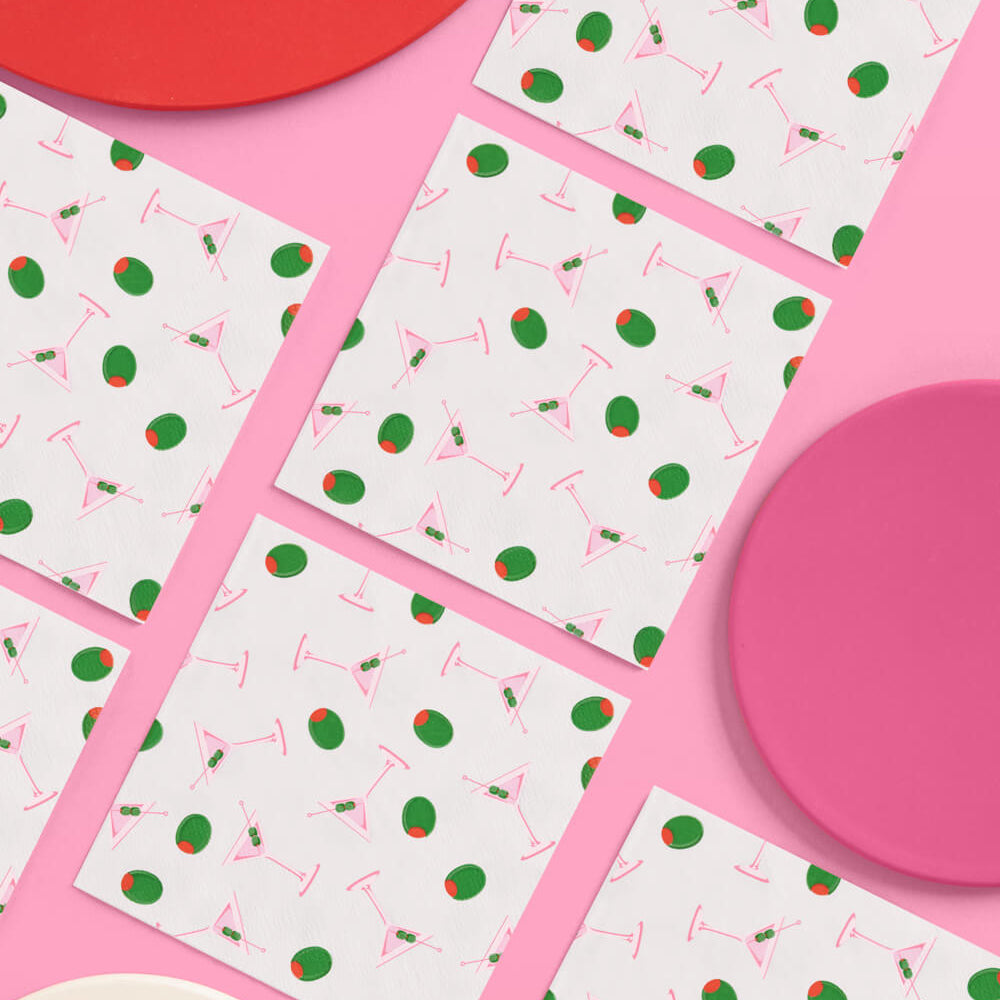 Patterned paper napkins with red and green designs on a pink background