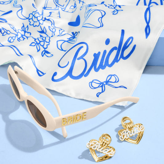 Beige sunglasses with 'BRIDE' on the arm, gold heart-shaped earrings, and a white scarf with blue designs and 'Bride' text.