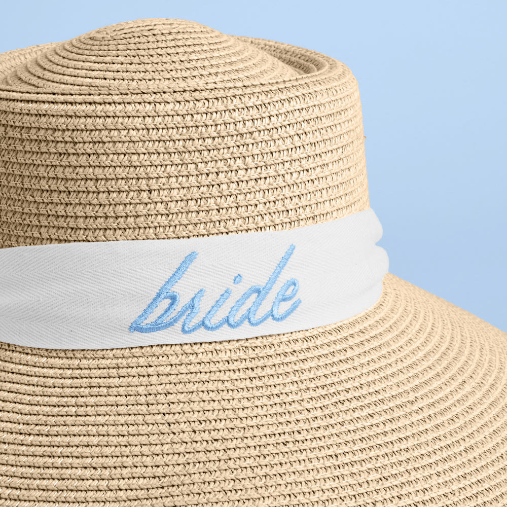 Beige straw hat with 'bride' band on a blue background