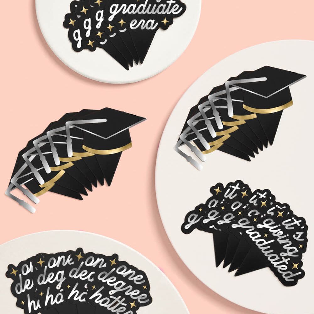 Graduation-themed coasters with decorative text and designs on a pink background