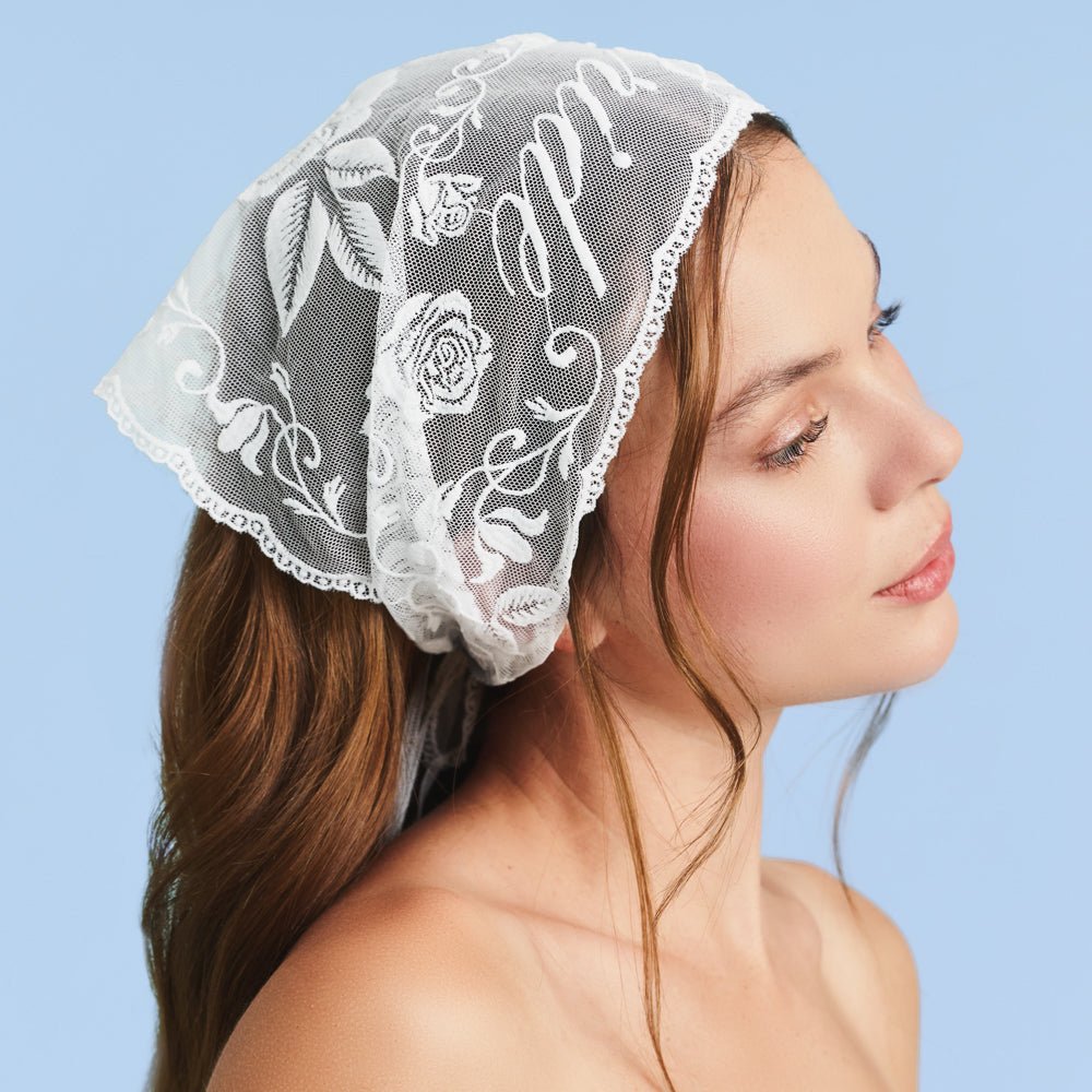 Woman wearing a white lace bonnet against a light blue background