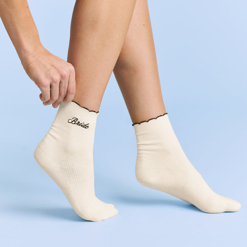 Person wearing white socks with 'Bride' text on a light blue background