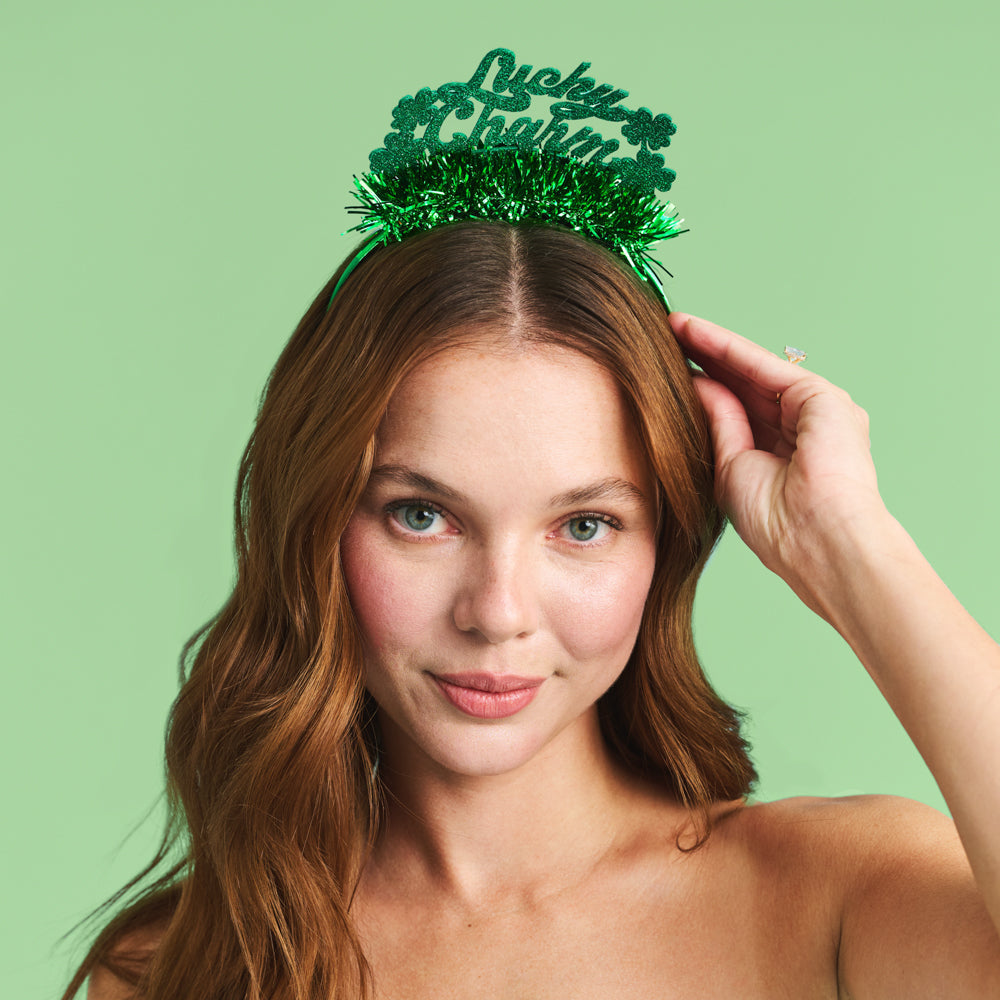 Woman wearing a green 'Lucky Charms' tiara against a light green background