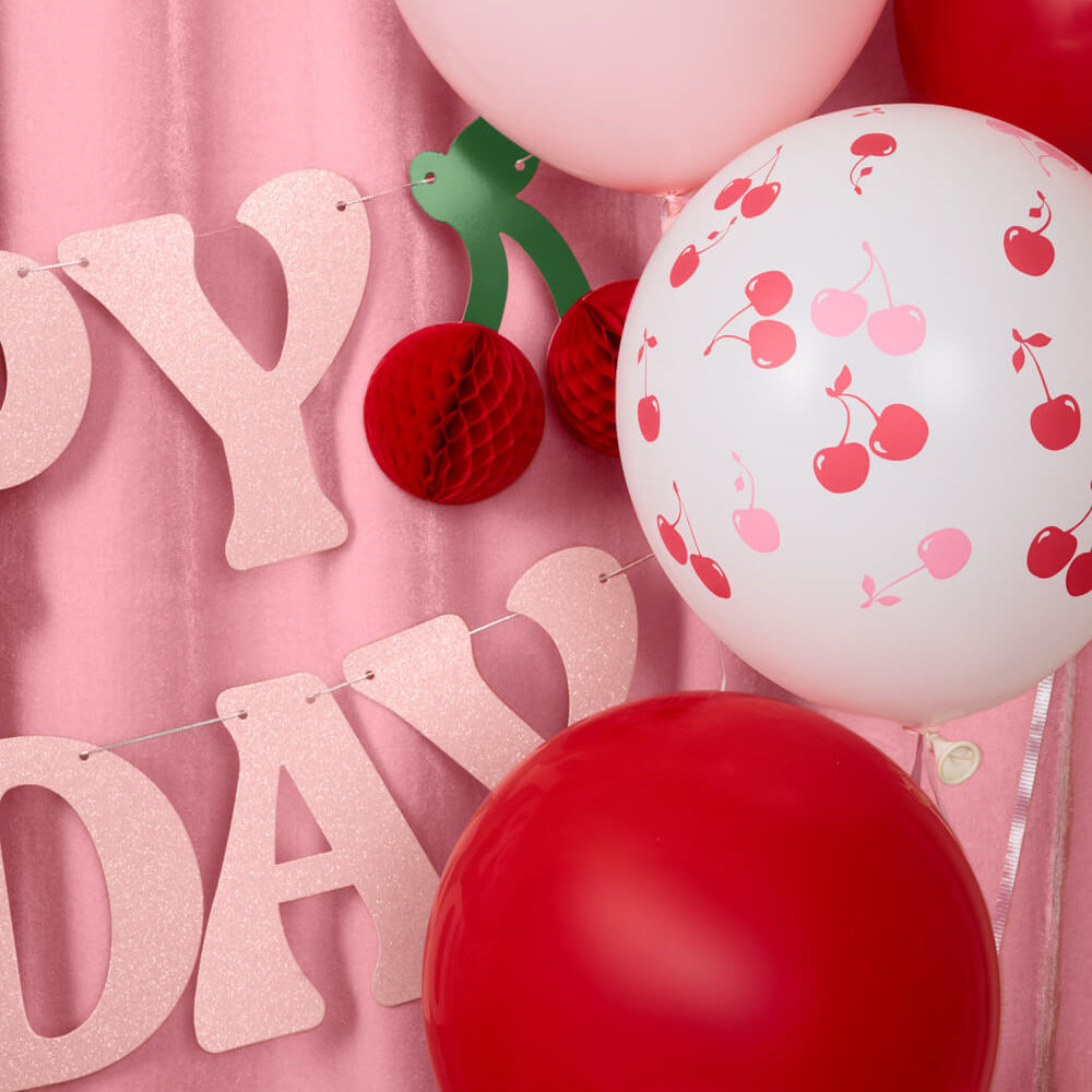Decorative setup with balloons and 'Happy Birthday' banner on a pink background