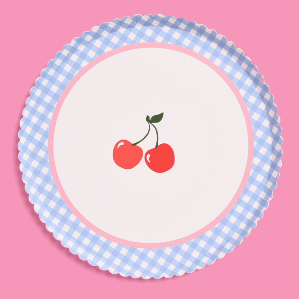 Round paper plate with blue checkered rim and red cherries on a pink background