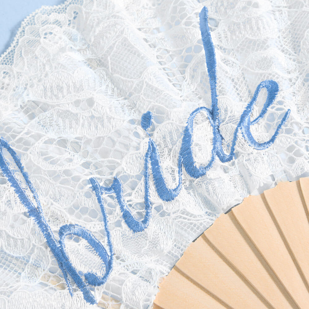 White lace garter with blue 'bride' embroidery on a light blue background