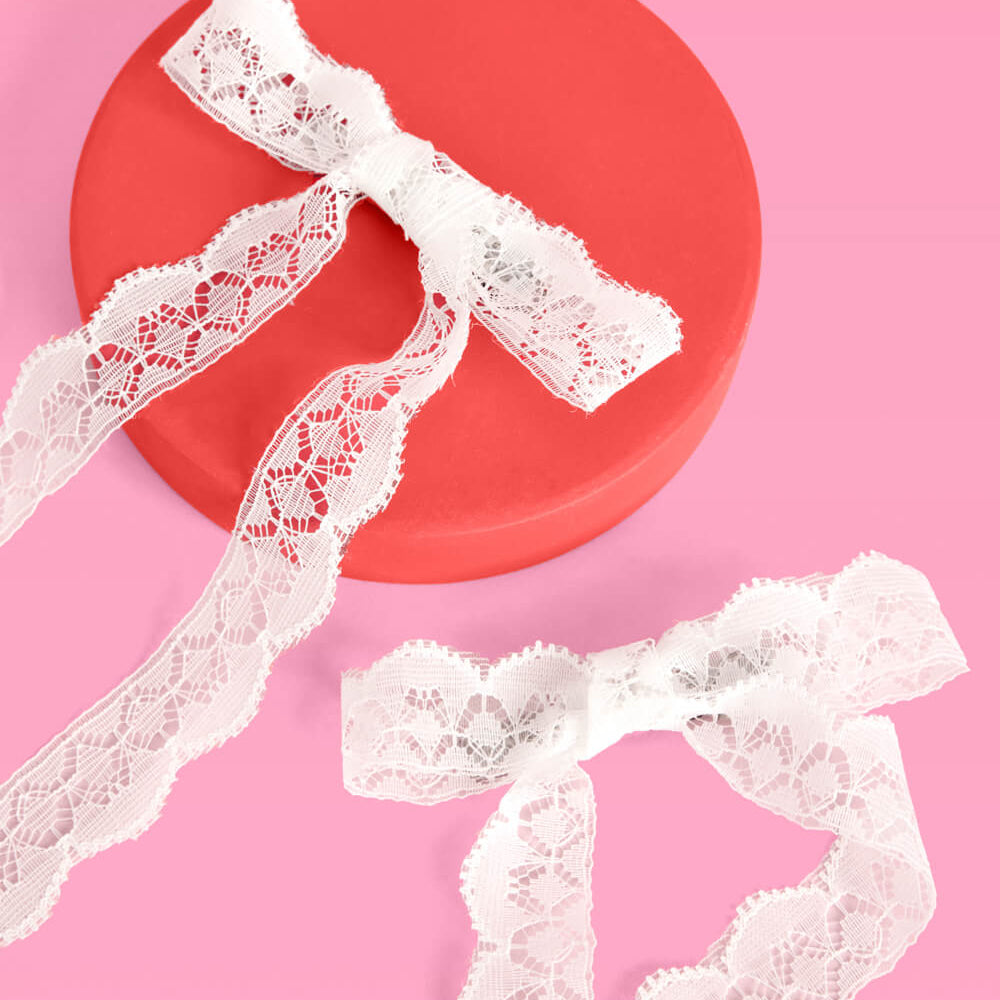 White lace trim on a pink background with a red circular object.